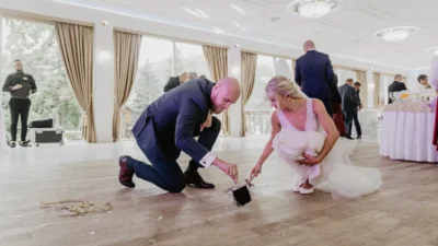 Fotografia ślubna – para młoda sprzątająca rozbite szkło